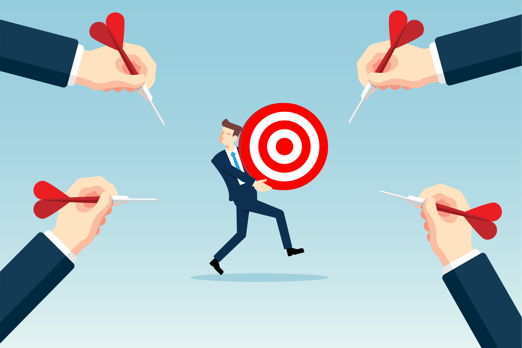 A businessman holds a dartboard as four hands toss darts at it.