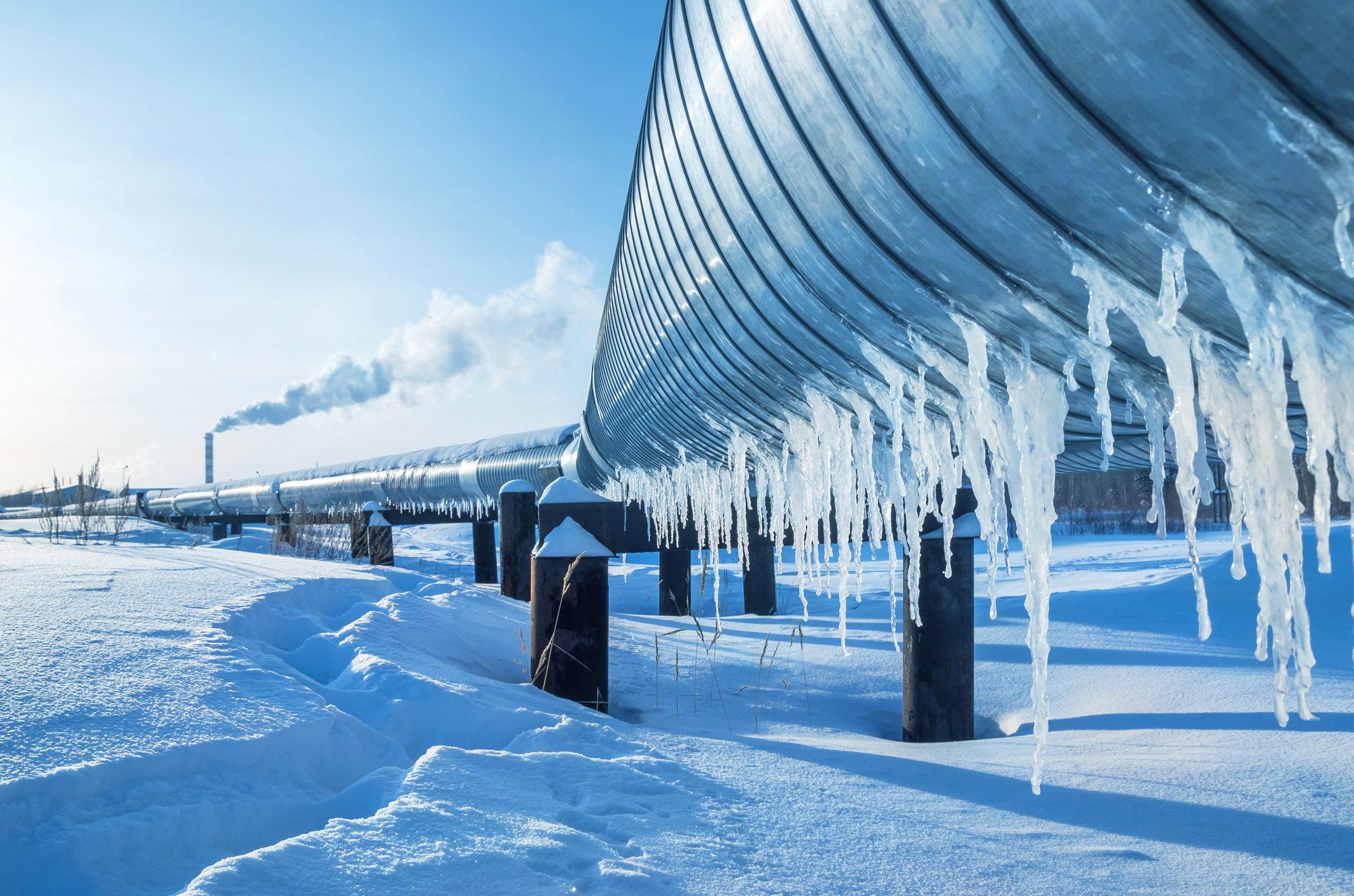 An icicle-covered pipeline crosses a snowy landscape