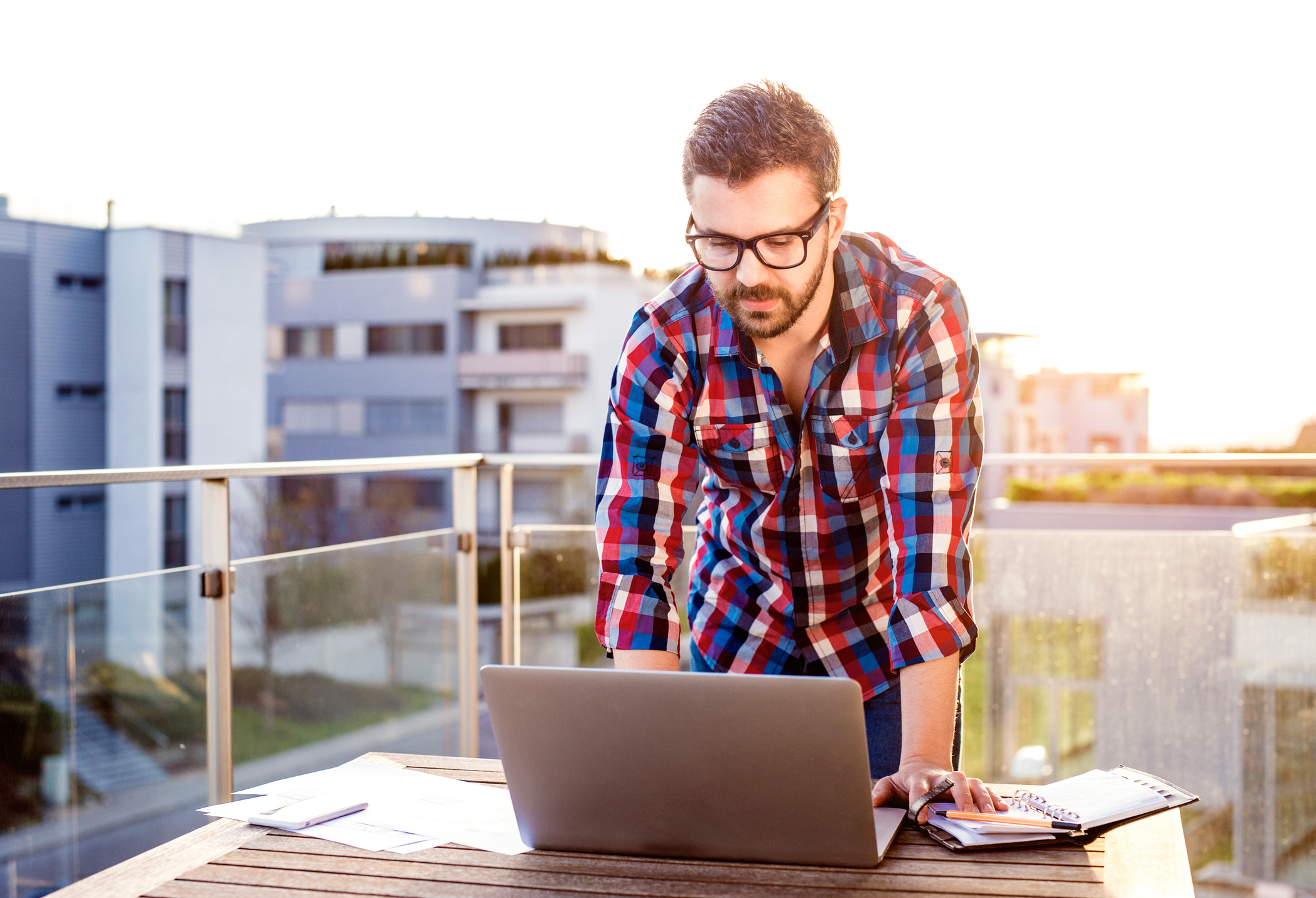 Man standing in front of table with laptop on a porch