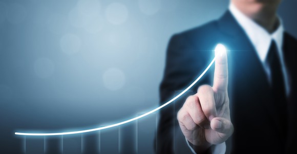 Businessman pointing to a line sloping upward 