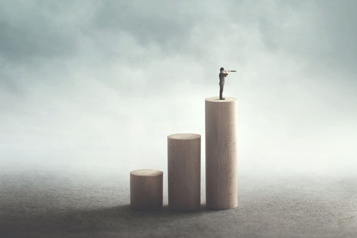 On a series of progressively taller cylinders, symbolizing an upward sloping chart, a man stands atop the tallest pillar looking through a telescope.