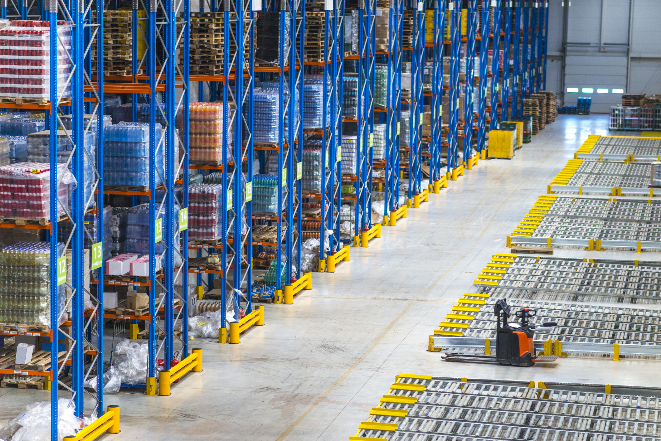 Top view of large storage area in a distribution warehouse interior with goods on the shelf and forklifts