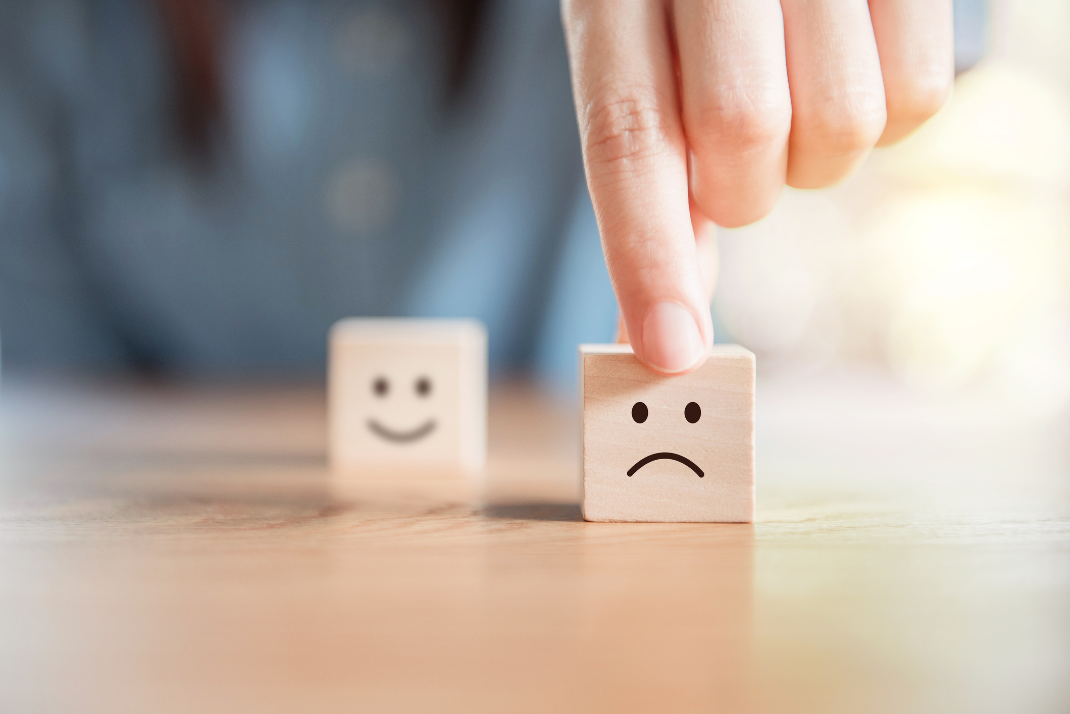 Hand touching a die decorated with a sad face