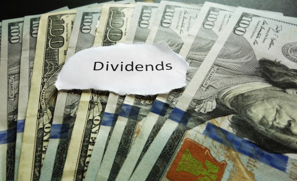 A torn slip of paper with "dividends" printed on it on top of $100 bills