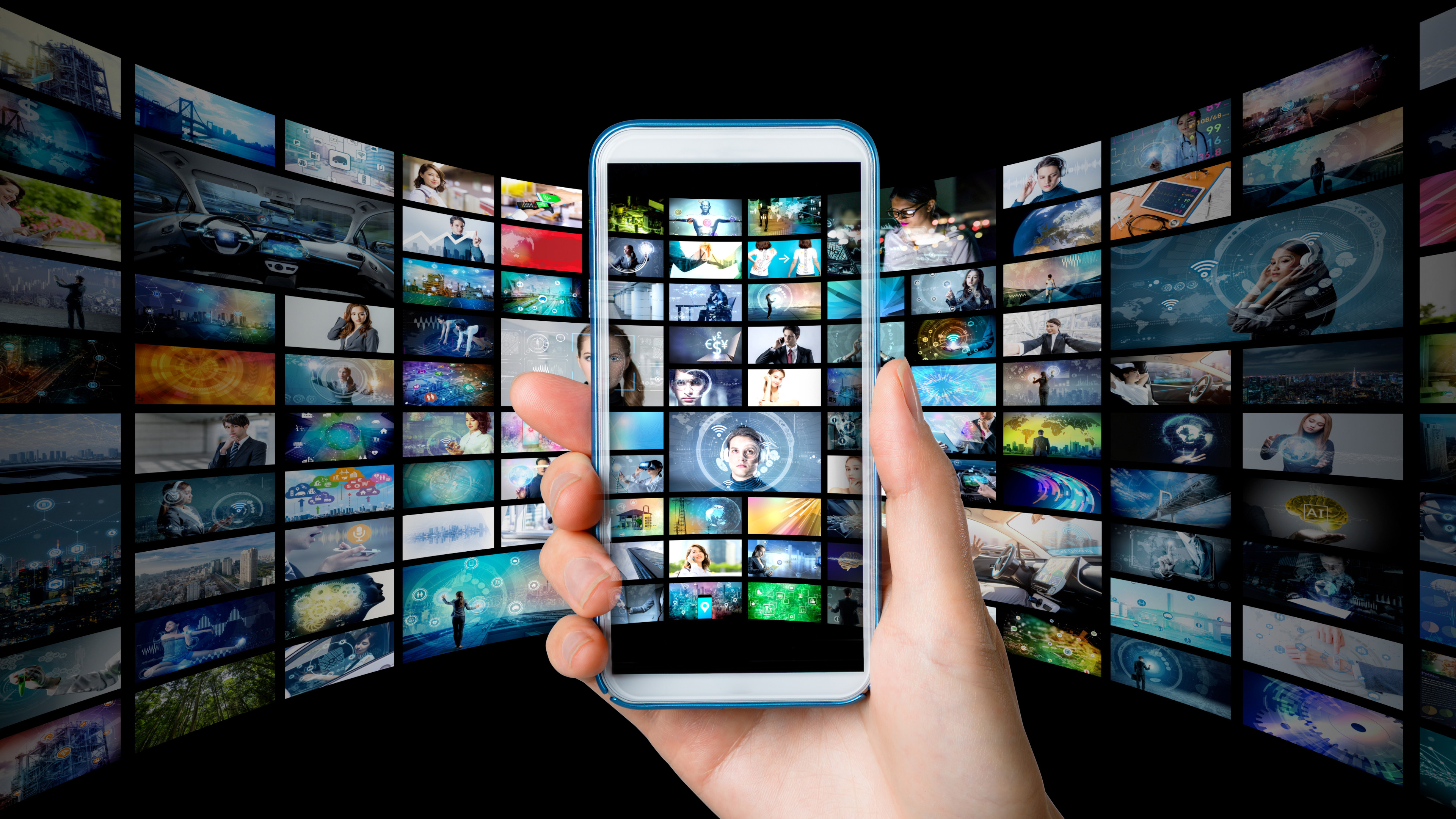 Hand holding a phone displaying video library with dozens of titles.