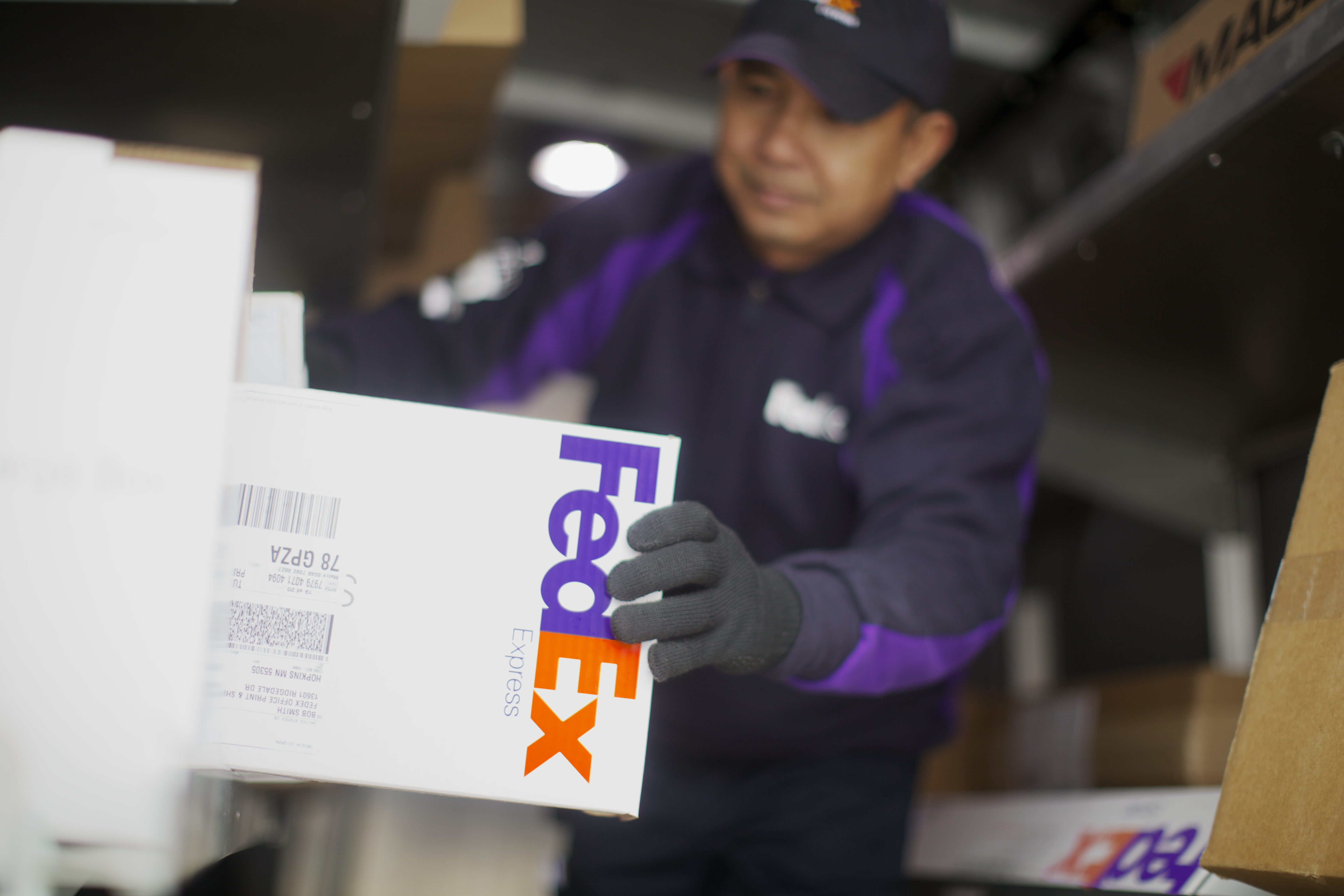 A FedEx delivery person grabs a package off a shelve in preparation for delivery