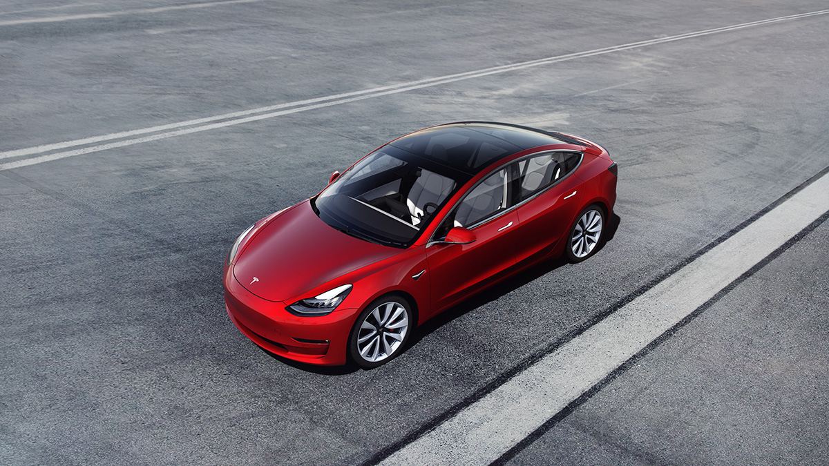 A Tesla Model 3 parked on a wide road.