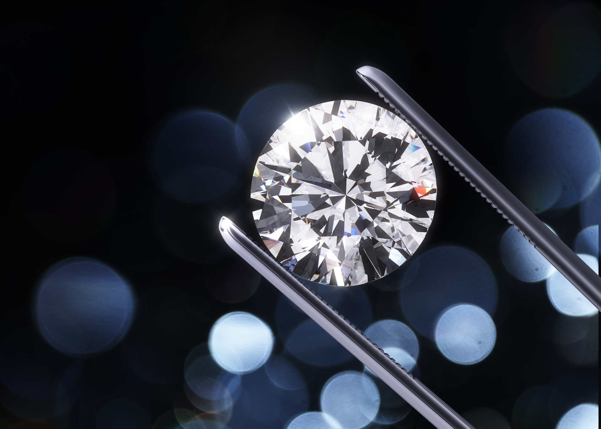 Diamond held in jeweler's tweezers.