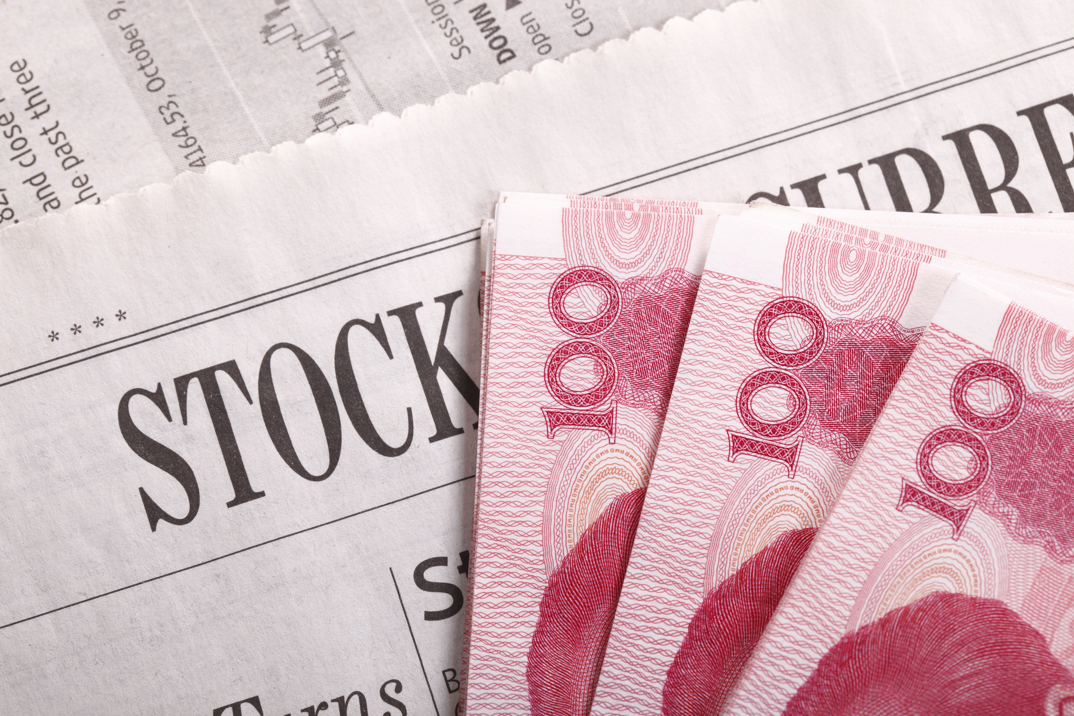 Chinese yuan notes atop a newspaper stock-market section