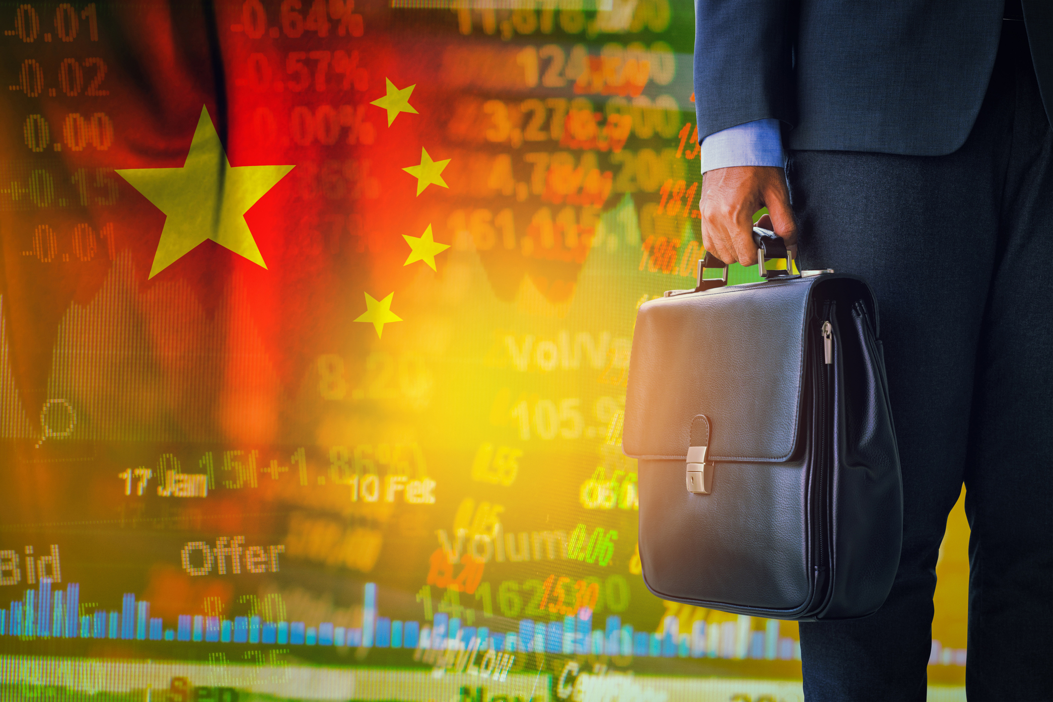 A man in a suit holding a brief case with the Chinese flag in the background