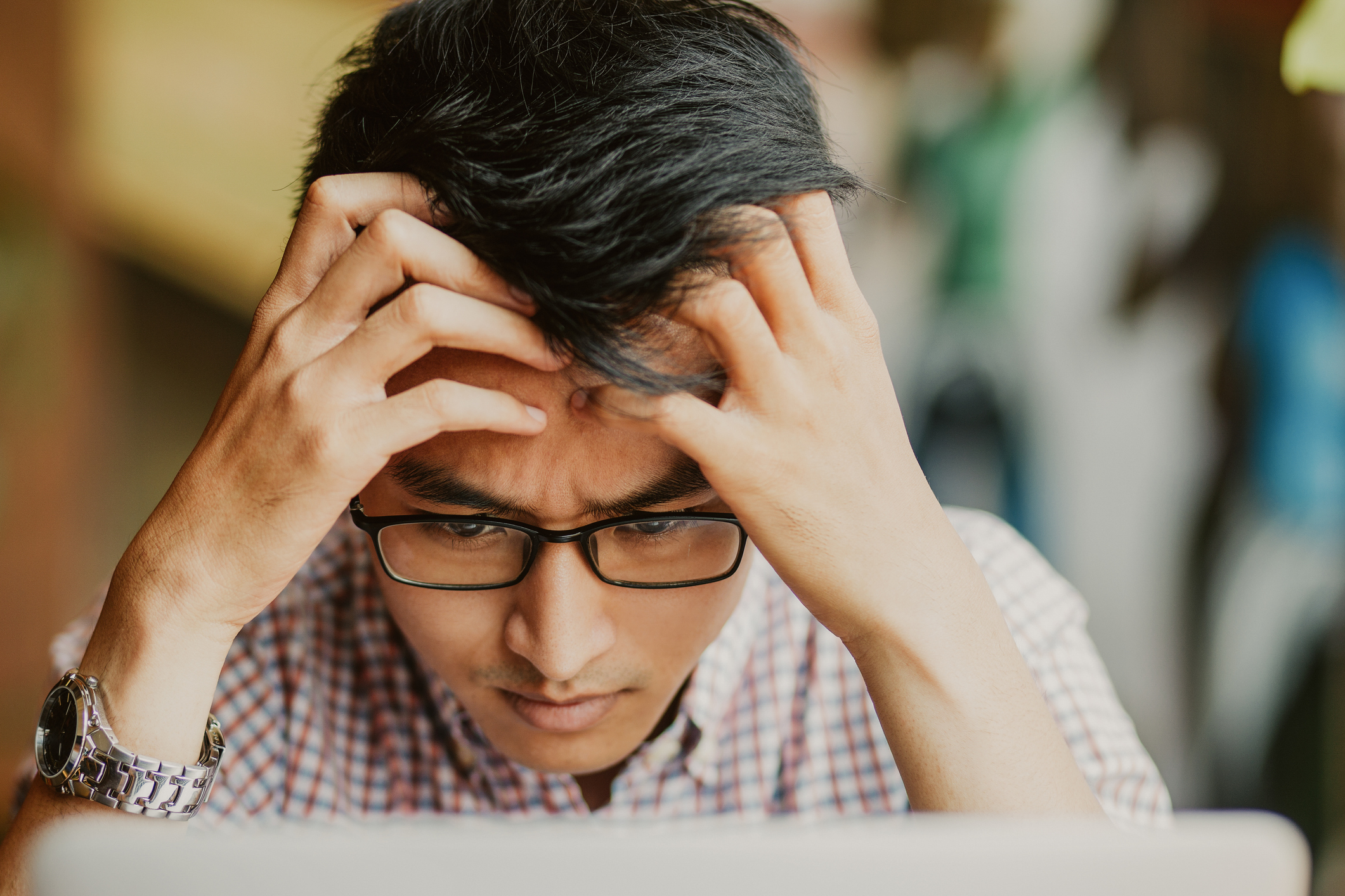 Man at laptop holding his head