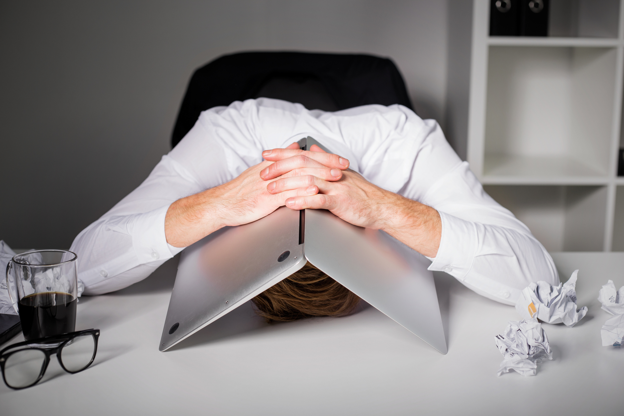 Upset man with his head under his laptop