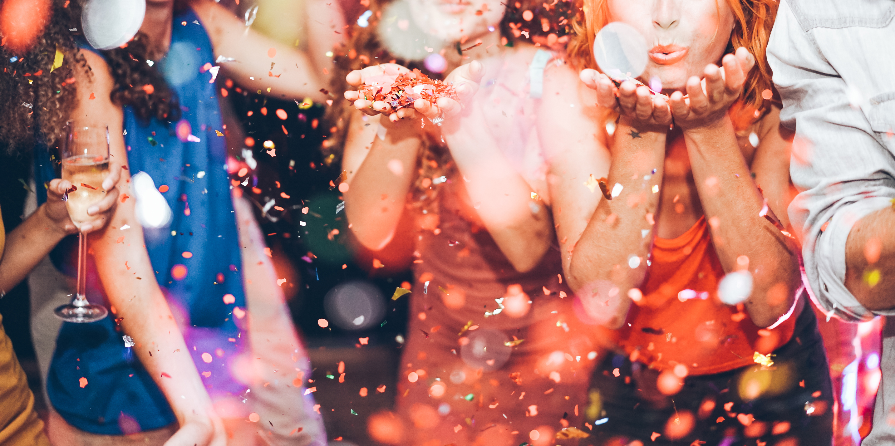 A group of party-goers blow confetti.