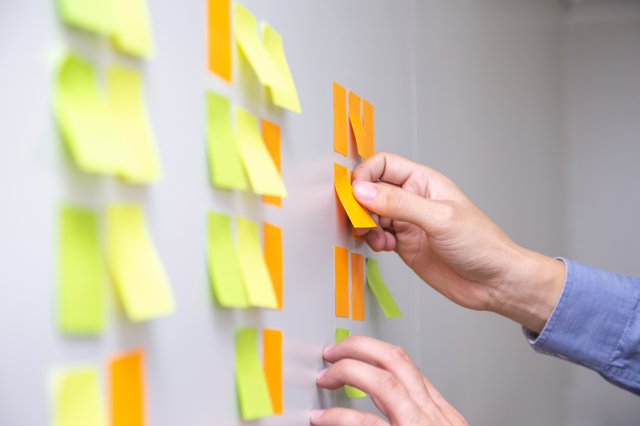 A man places PostIt Notes on a white board.