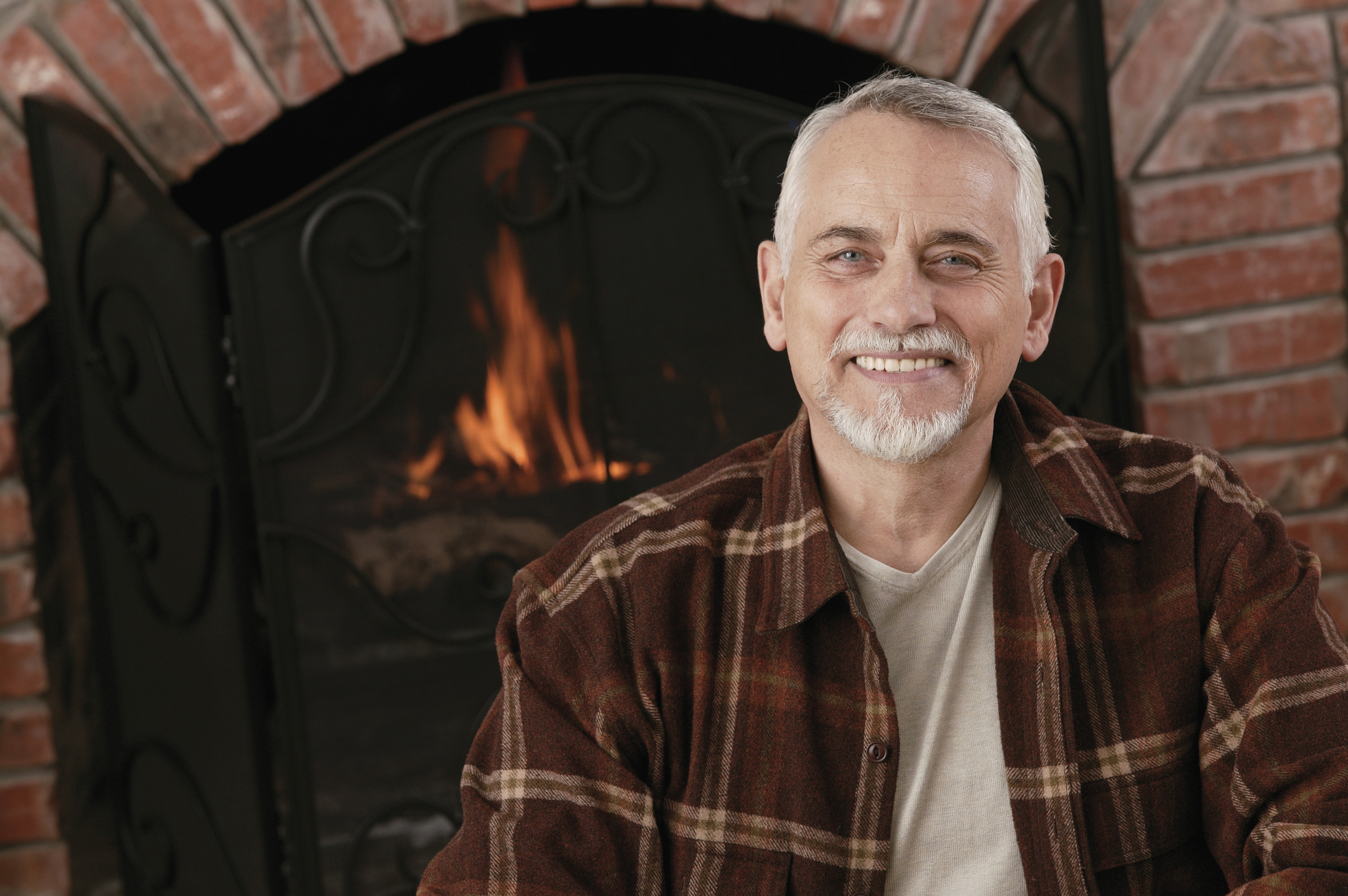 Smiling older man in front of fireplace