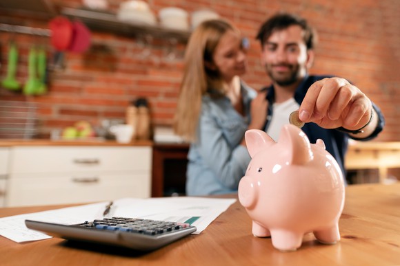 Man putting money into a piggy bank.