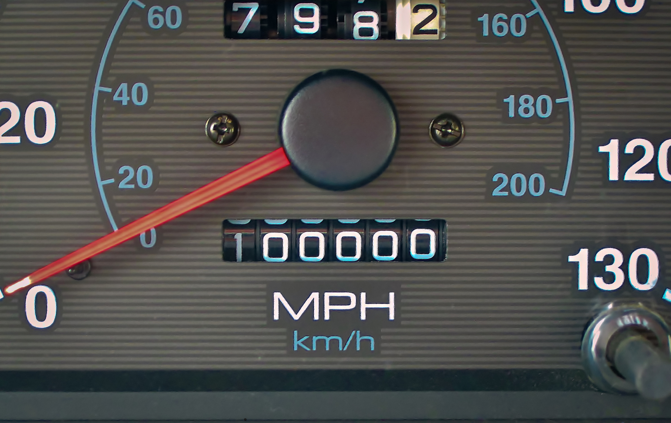 We see a close-up of a car's odometer, at 100,000 miles, is shown.