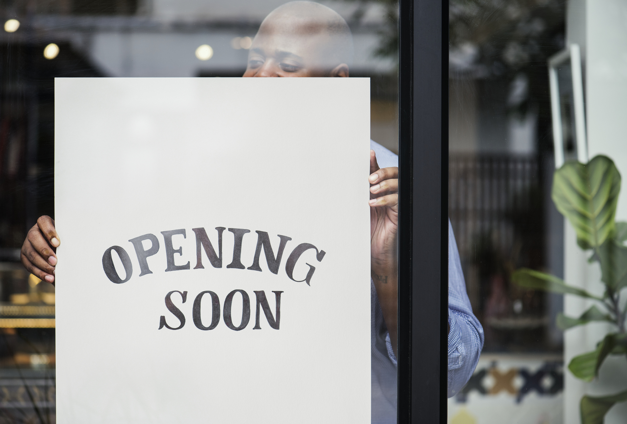 Man hanging sign that says opening soon.
