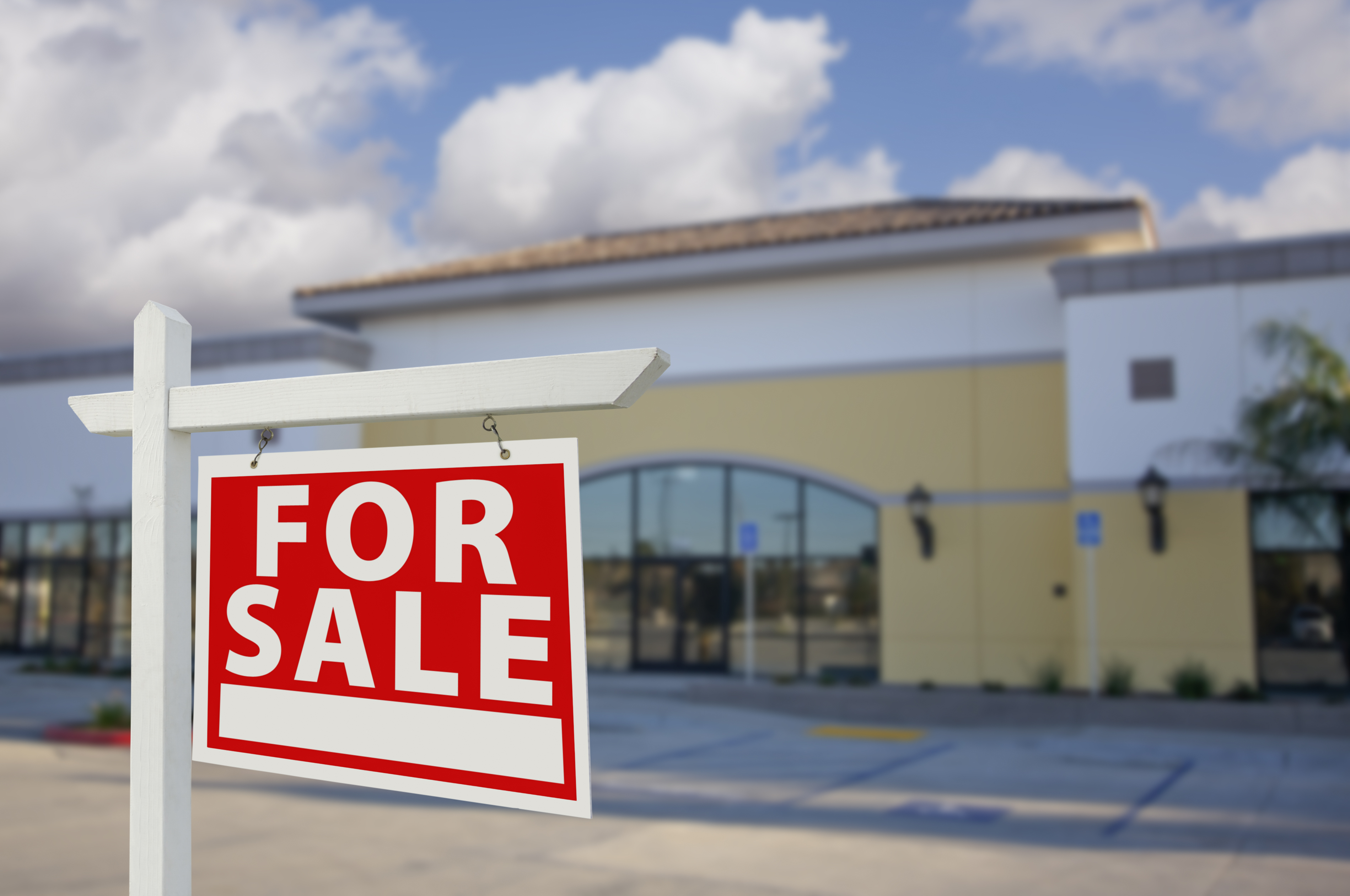 A "For Sale" sign in front of an abandoned store.