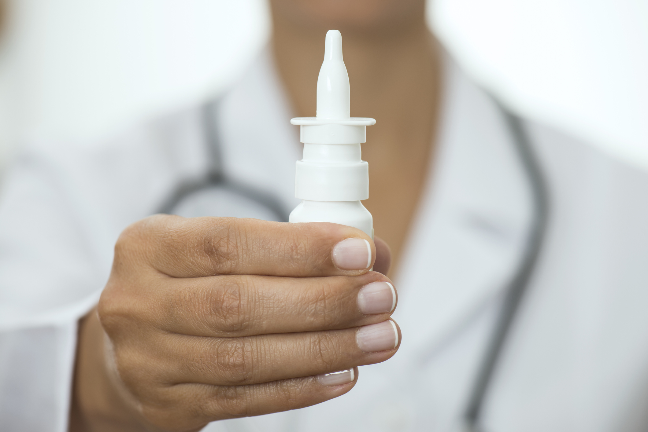 Medical professional holding a nasal spray in their hand.