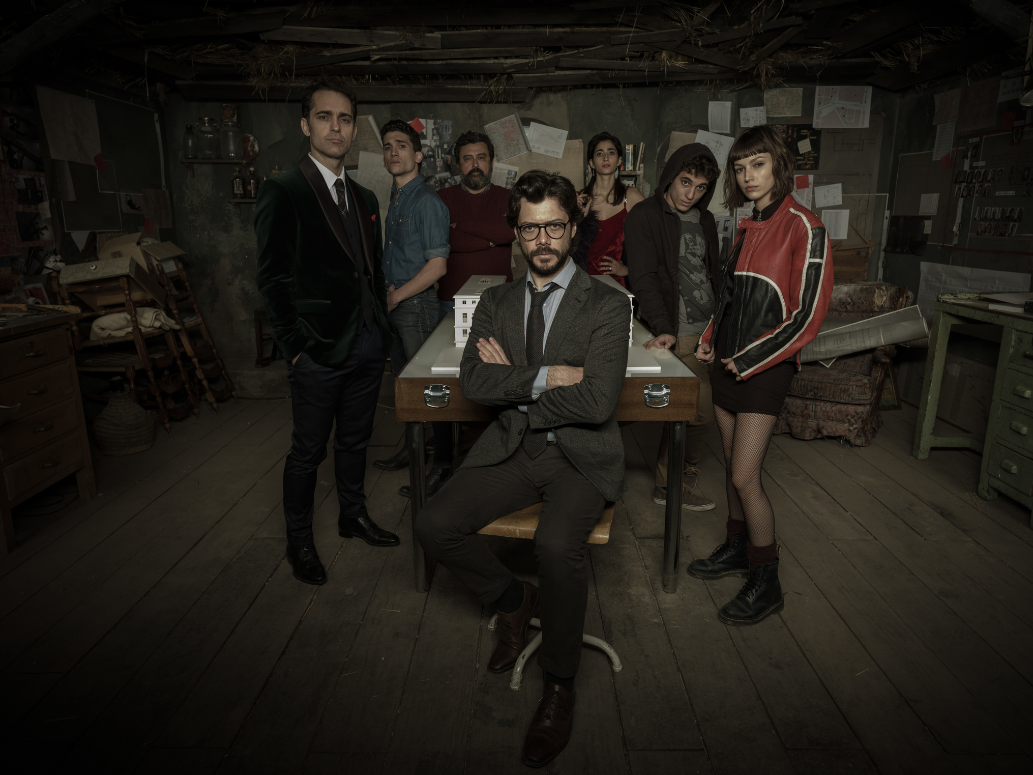 Seven people posing in a dimly lit room.