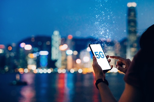 Person holding phone that says "5G" in front of city skyline