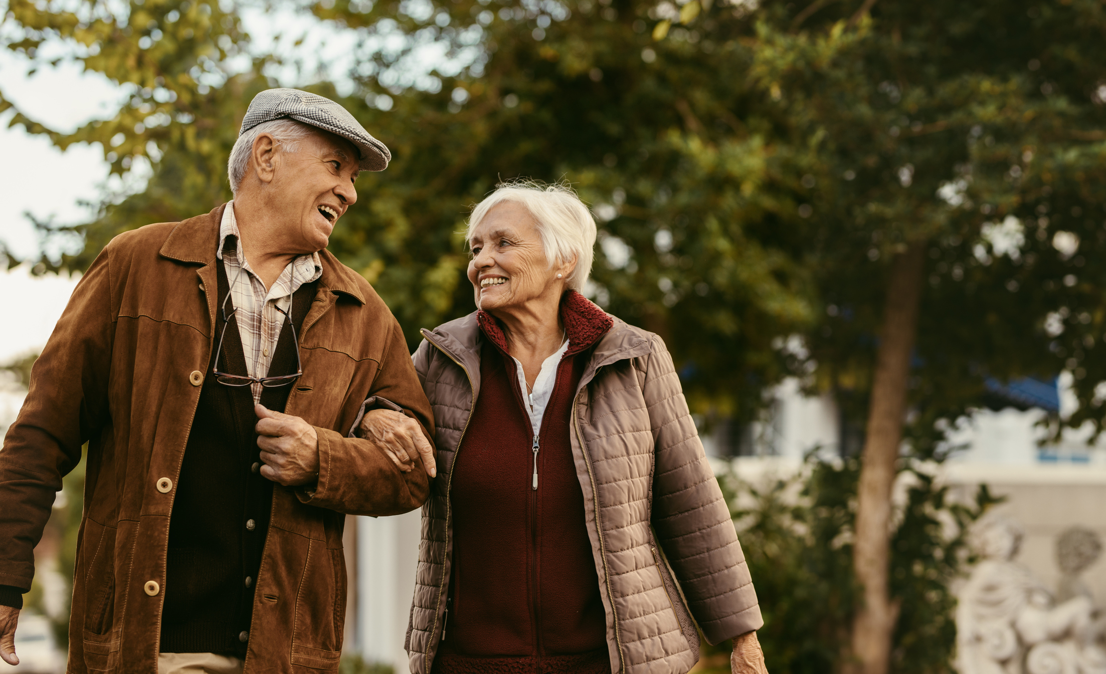 Smiling older man and woman linking arms and walking outdoors