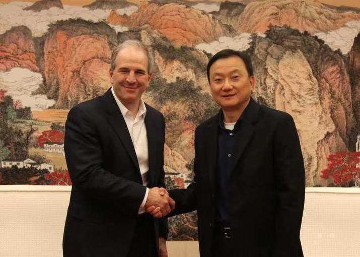 Jim Magats and Larry Wang smiling and shaking hands