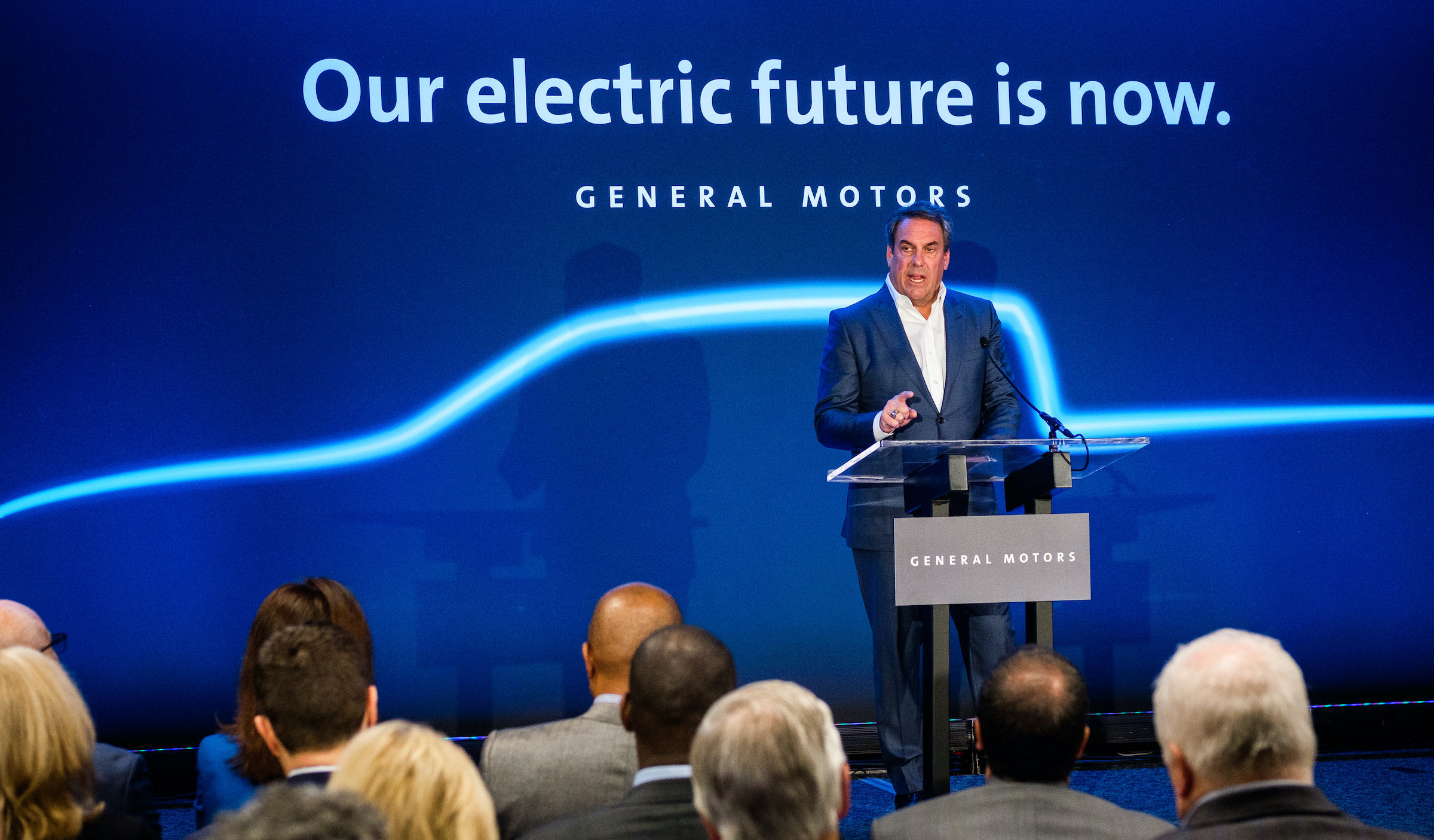 Reuss is standing at a podium before a backdrop with an outline of a pickup truck.