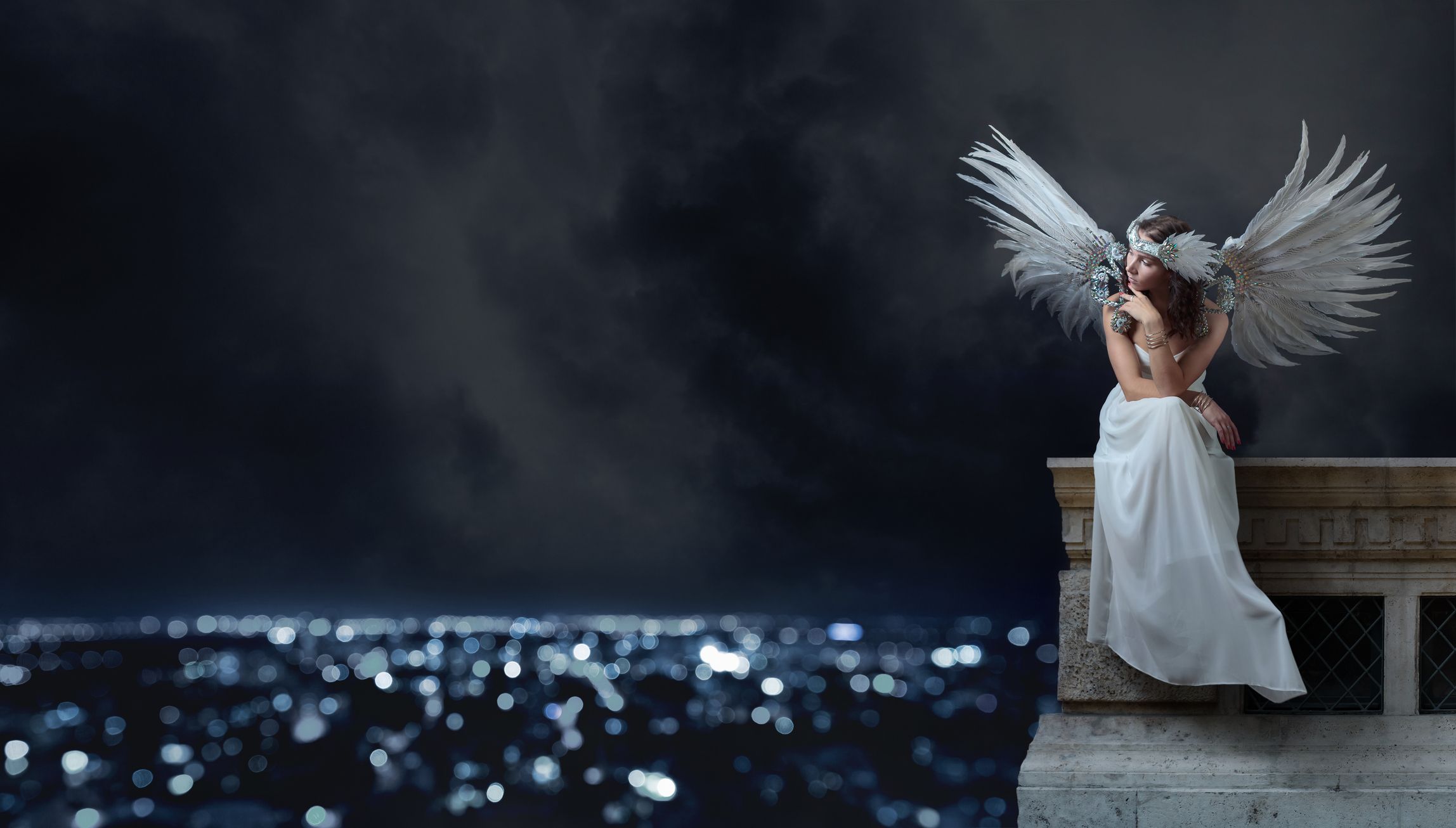 Woman in angels wings sits atop a building thinking