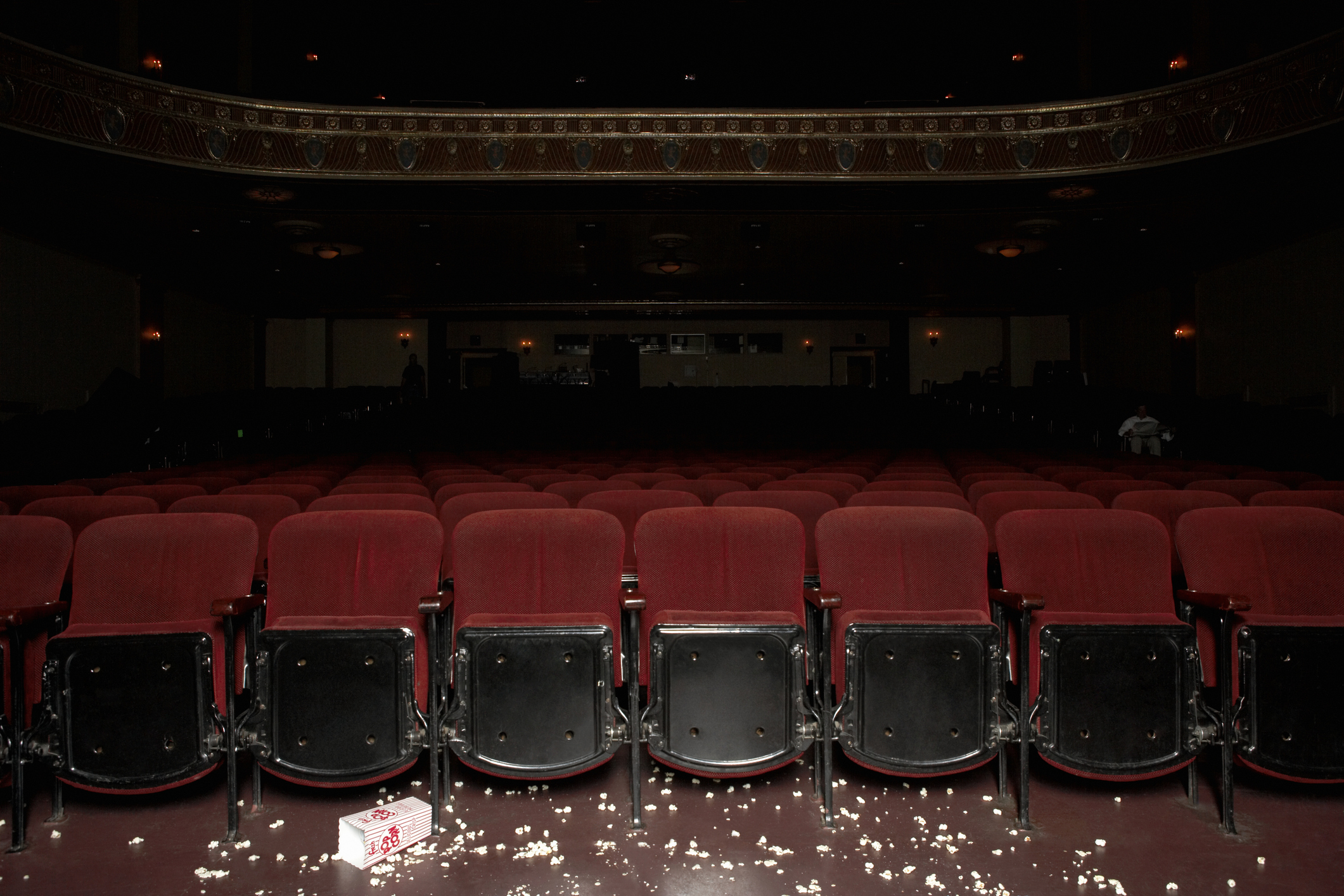 Darkened empty movie theater with floor littered with popcorn