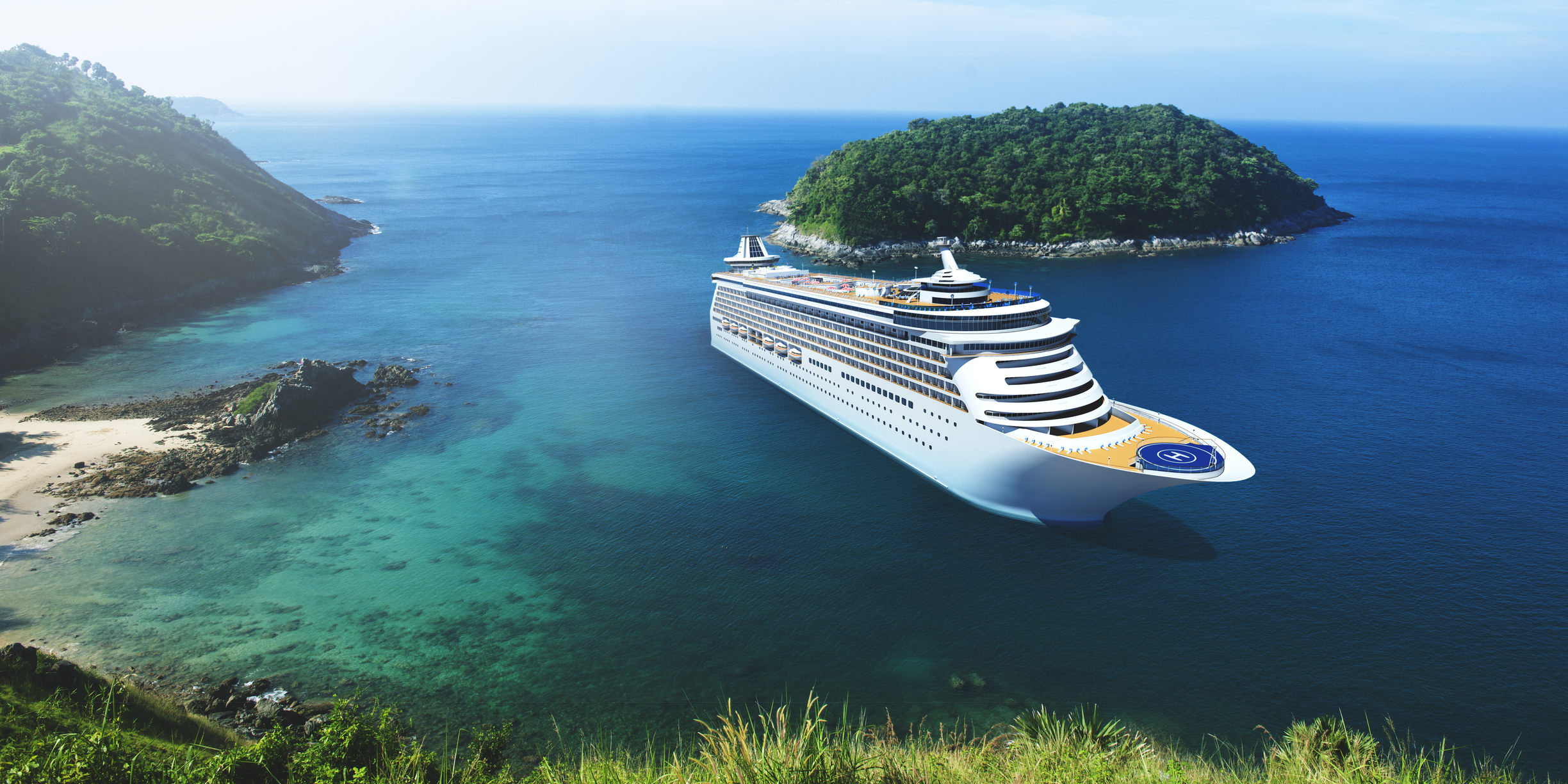 A cruise ship sailing in blue water near a lush coastline.
