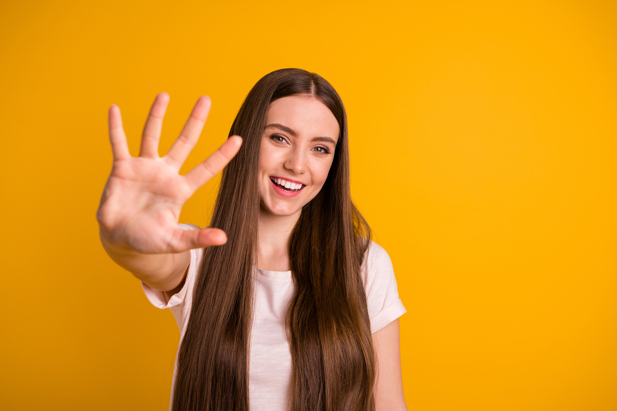 A teen girl holds up five fingers.