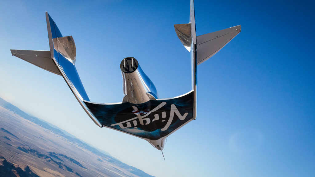 Close-up rear view of a Virgin spacecraft flying above the Earth.