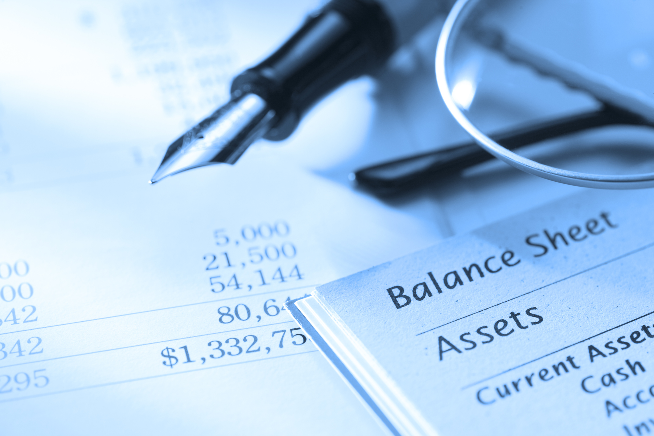 Multiple financial statements with a fountain pen and a pair of glasses.
