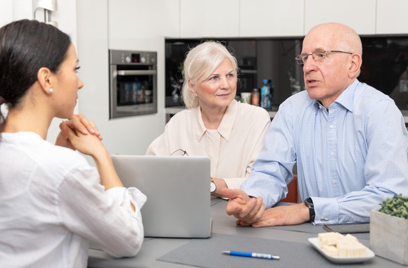 Older man and woman sitting across from woman at a table with a laptop