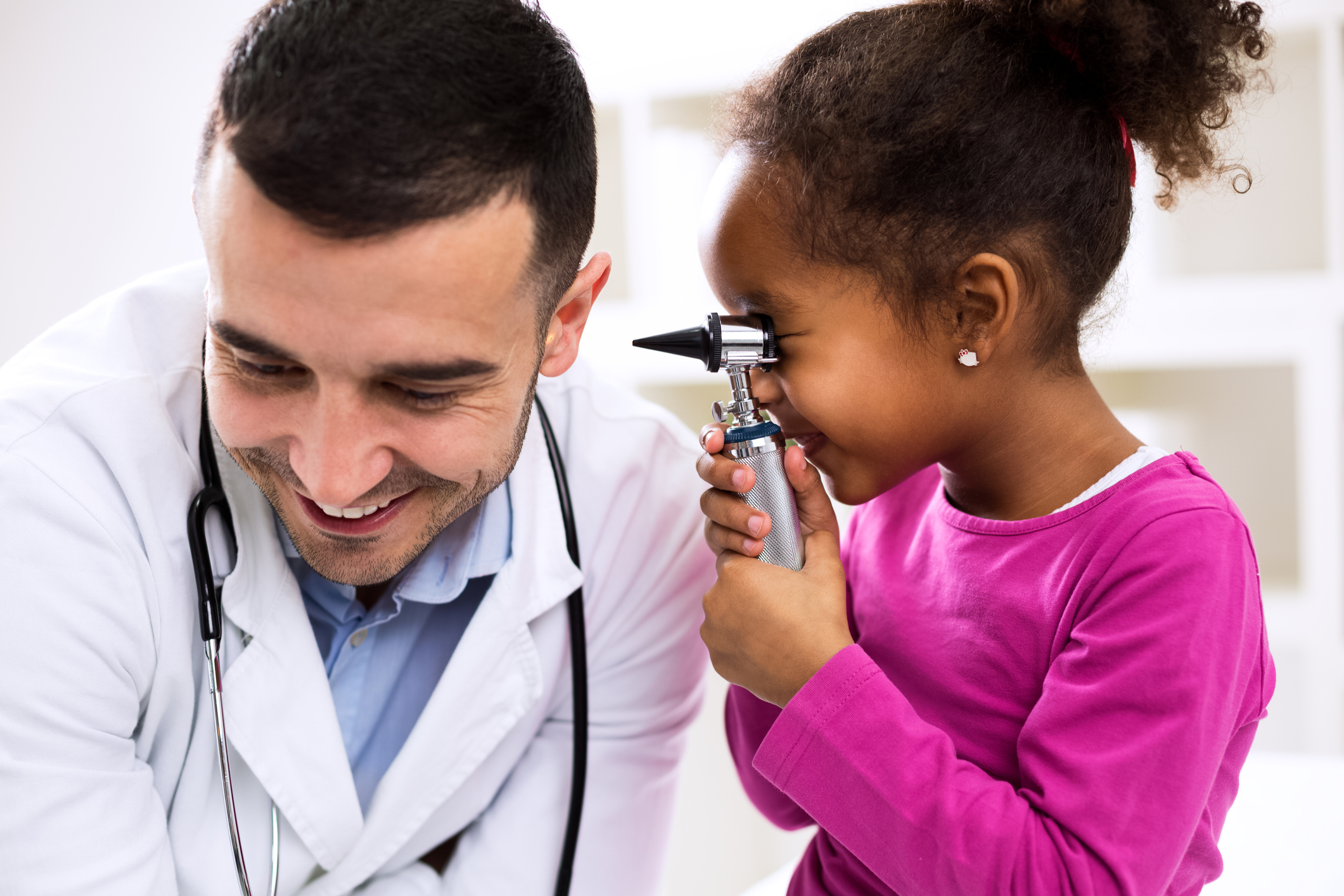 Male healthcare provide allows female child to play with his otoscope
