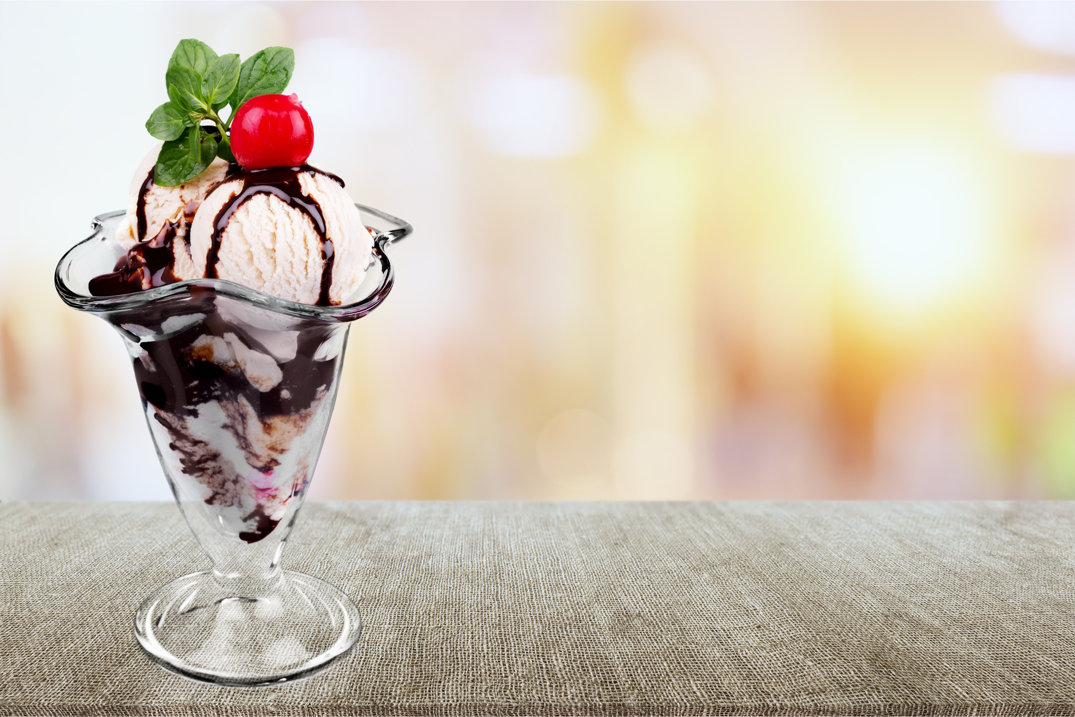 Vanilla ice cream with hot fudge and a cherry in a sundae glass.