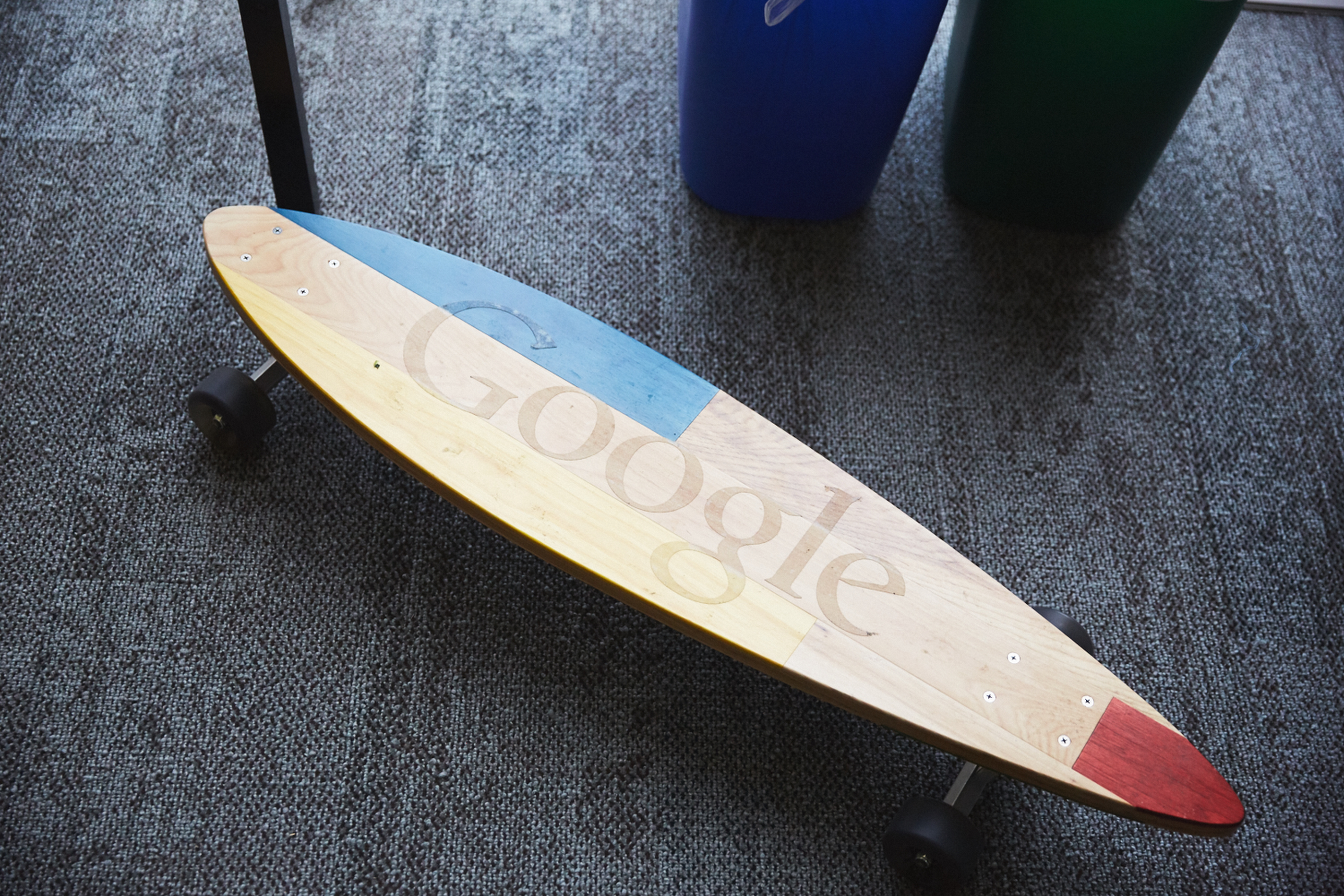 A Google skateboard on a dark office floor.
