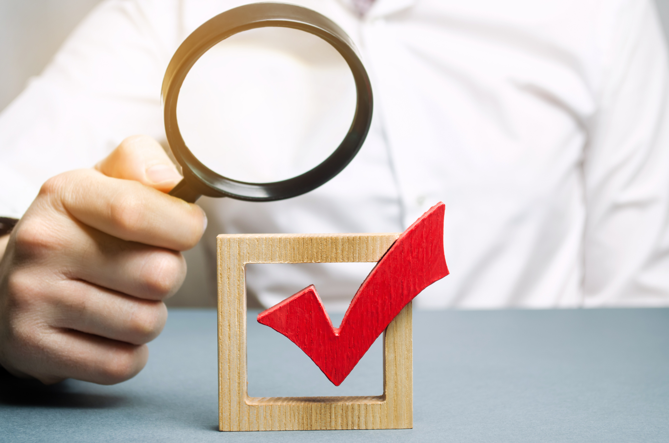man magnifying glass red check mark