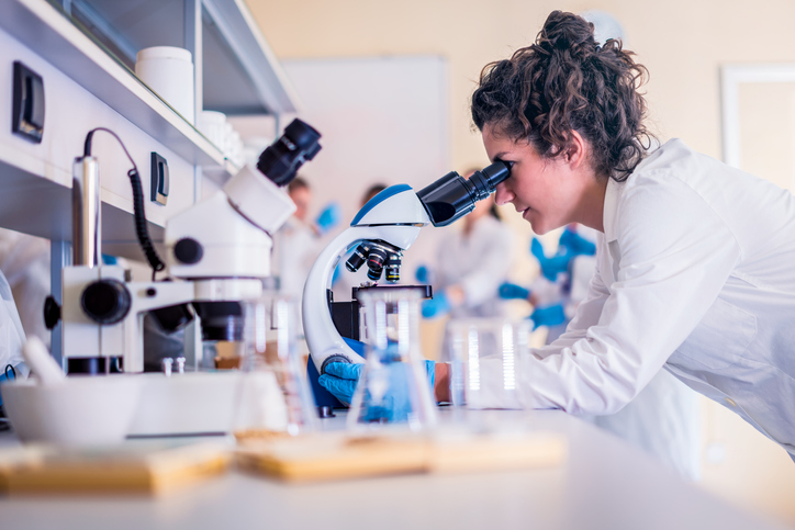 A scientist looking through a microscope.