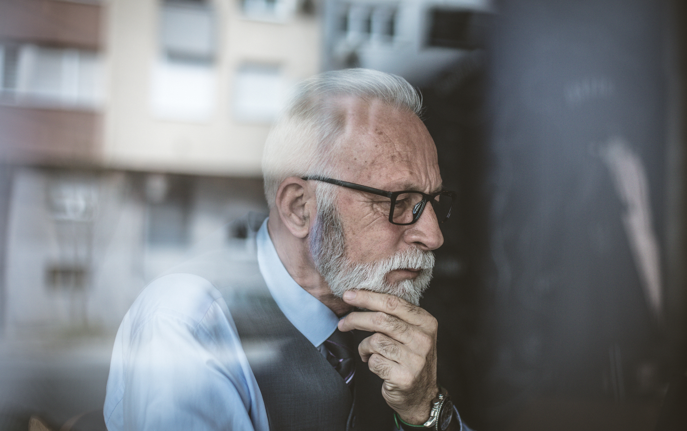 Older man resting chin on hand.