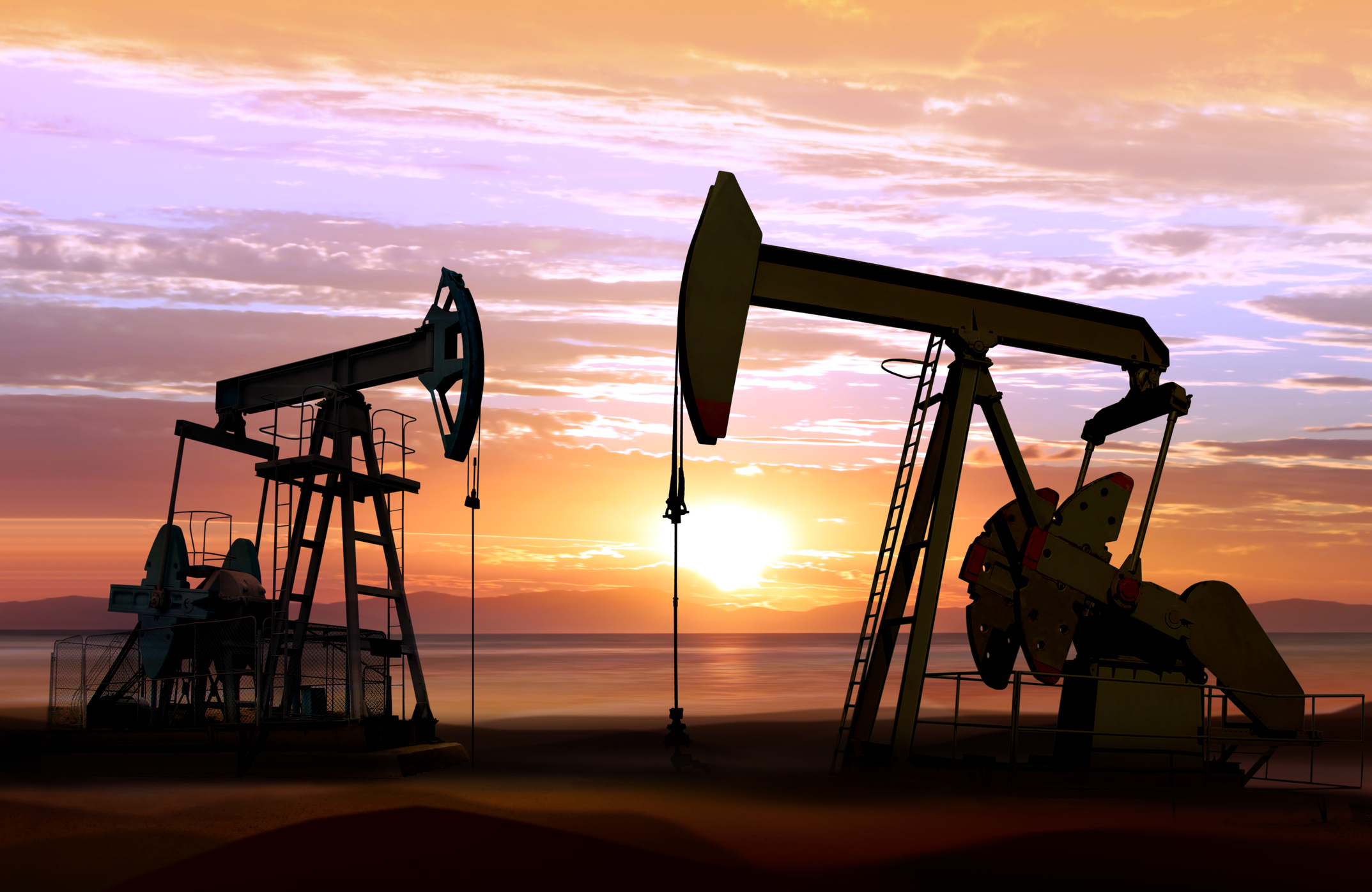 Two oil pumpjacks operating at sunrise. 