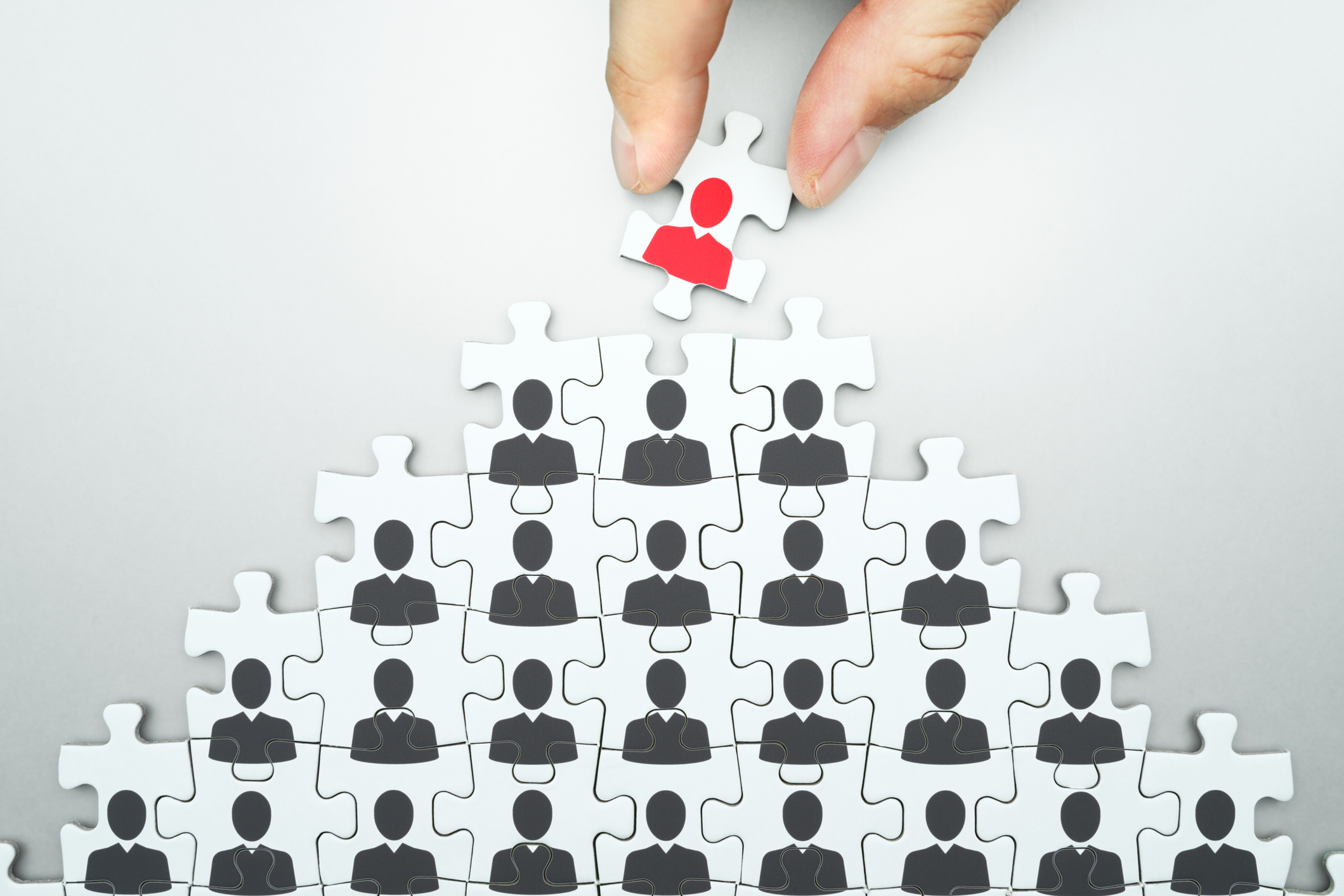 A jigsaw puzzle piece with a picture of a person being removed from the larger puzzle.