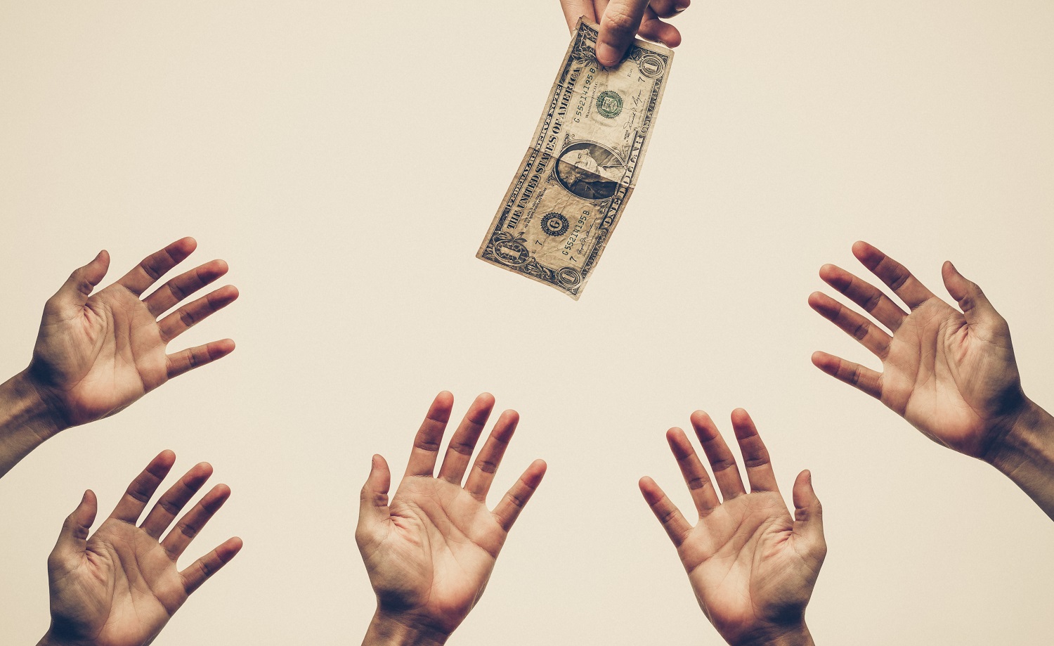 Hands reaching for a dollar bill.