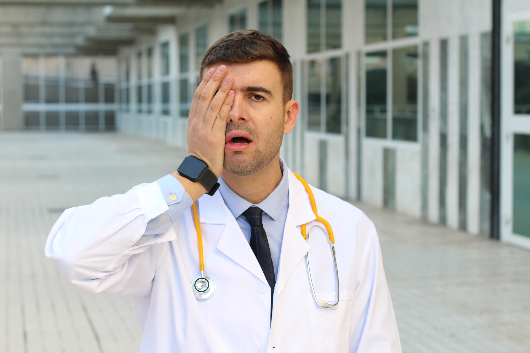 A doctor with a hand over one eye.