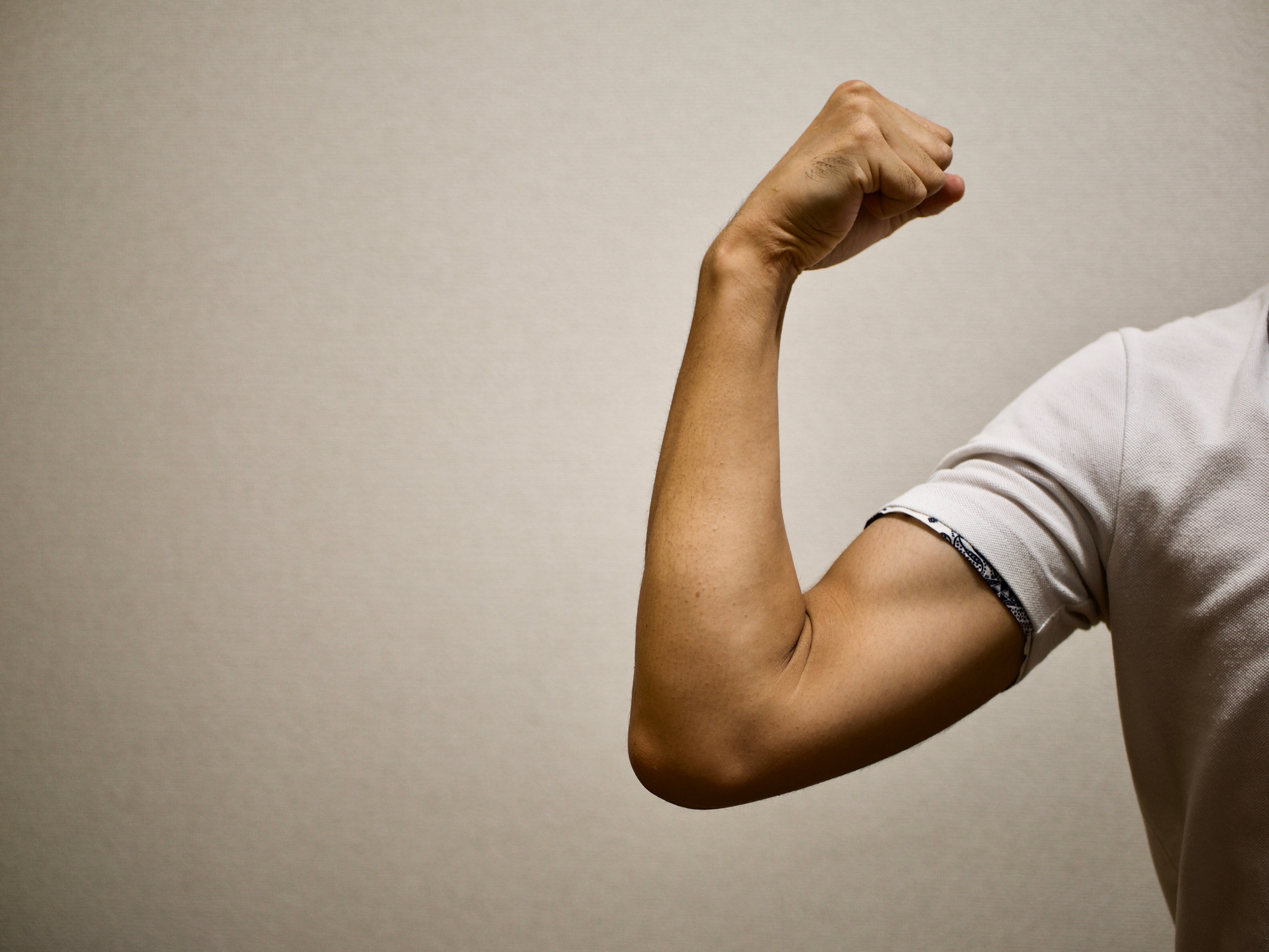 A man flexes his bicep in a tight T-shirt.