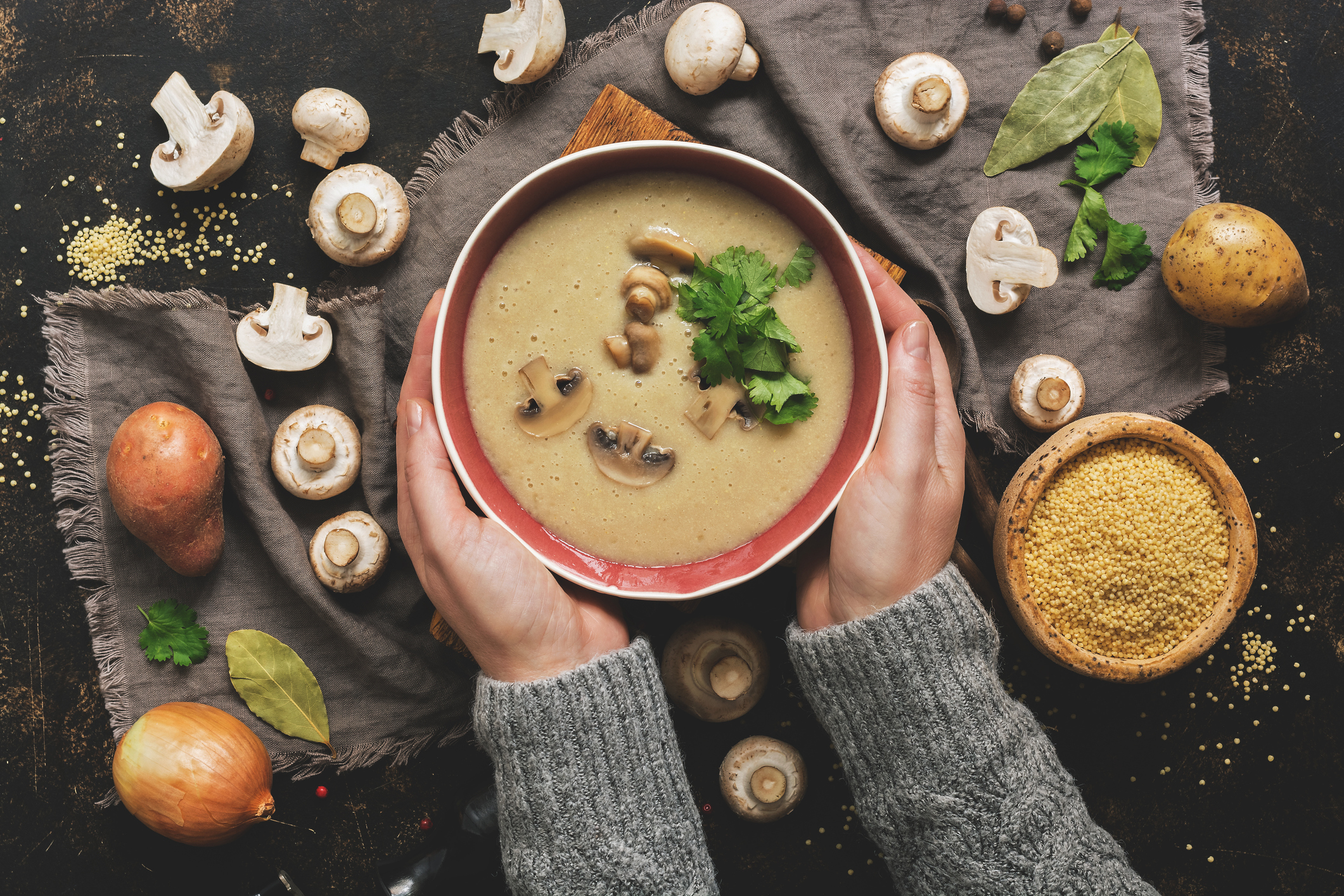 Bowl of soup surrounded by vegetables.