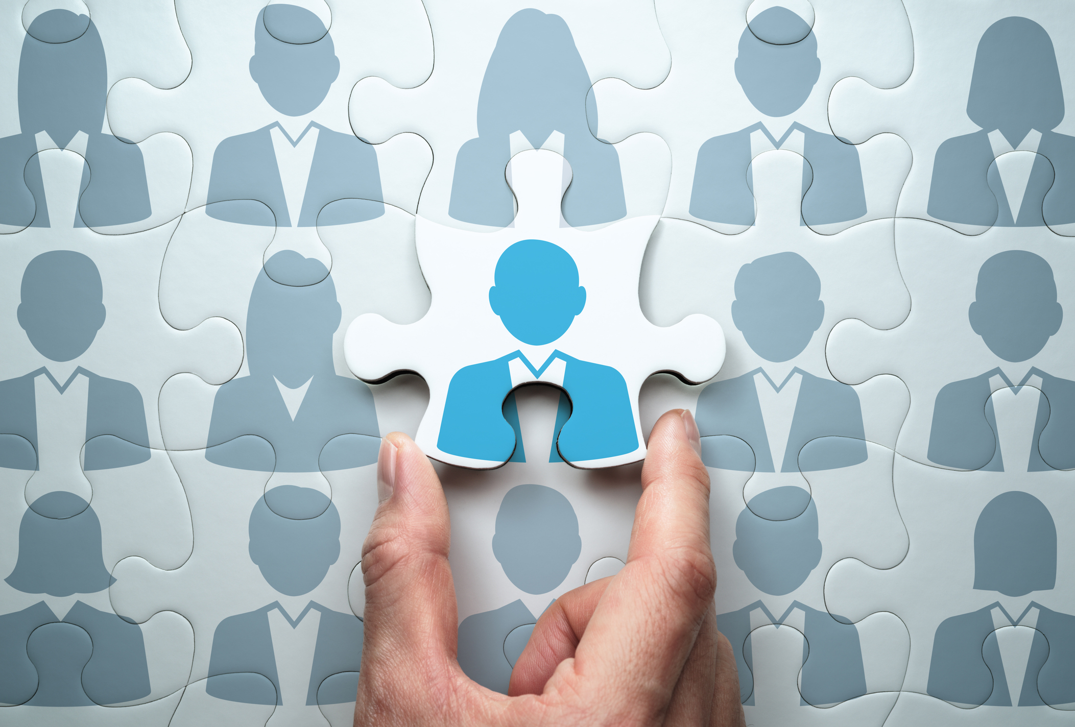Man's hand laying personnel puzzle piece in place