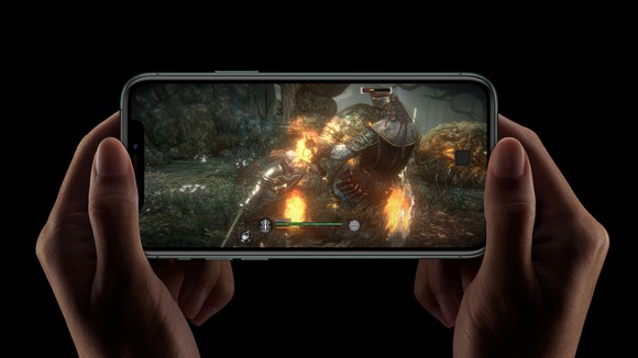 Two hands holding an iPhone 11 Pro that's displaying an image from a mobile game